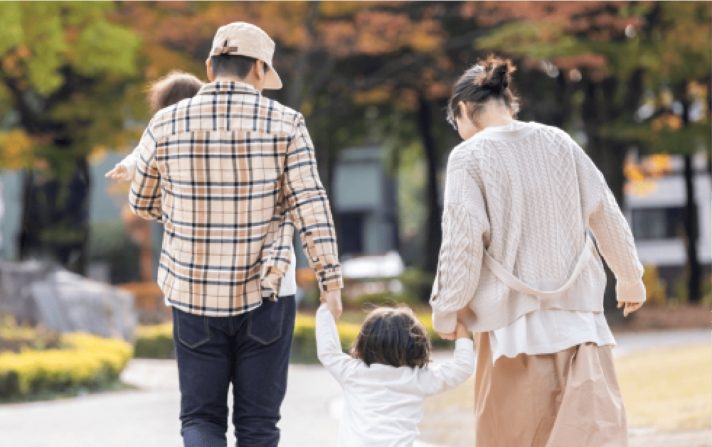 家族4人が手をつなぎ歩いている後ろ姿