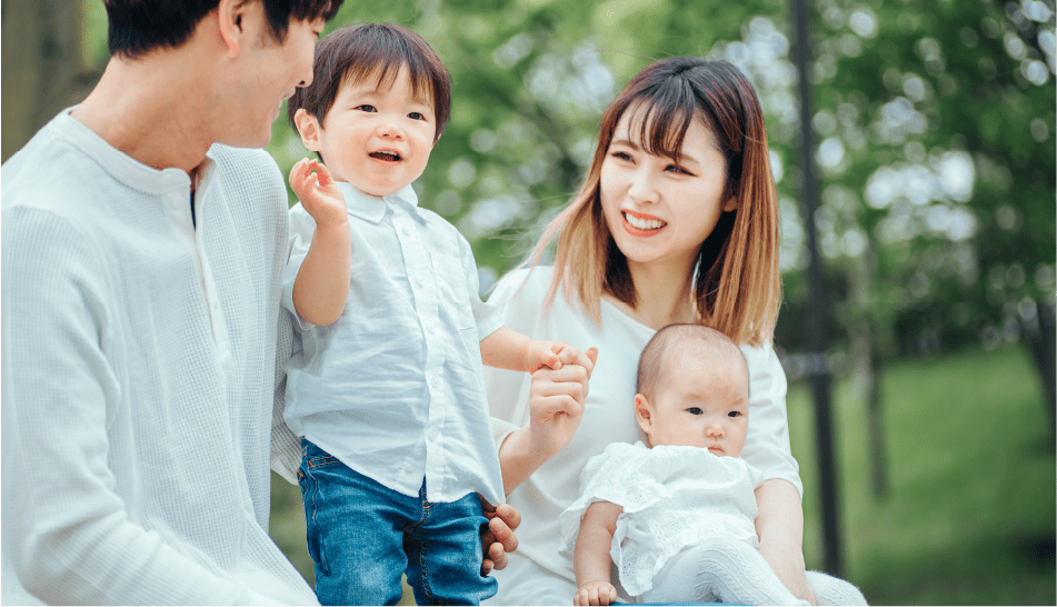 幼い2人の兄弟と両親が公園で微笑んでいる