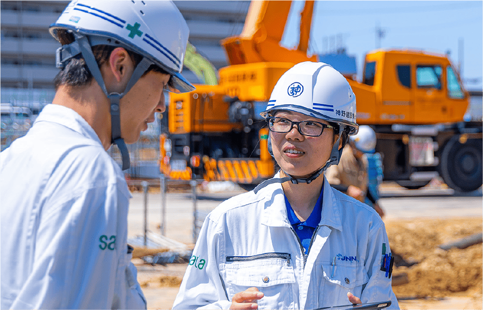 建築現場で打ち合わせをする二人の社員